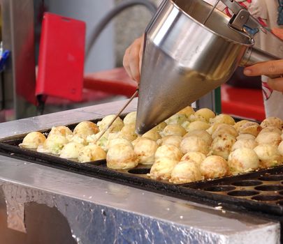 A street vendor makes balls filled with octopus meat and cabbage
