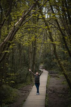 A young woman stood on a wooden pavement path in the countryside