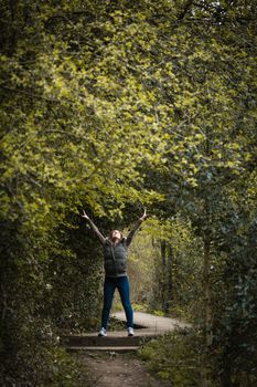 A young woman stood underneath an archway created by trees in the countryside