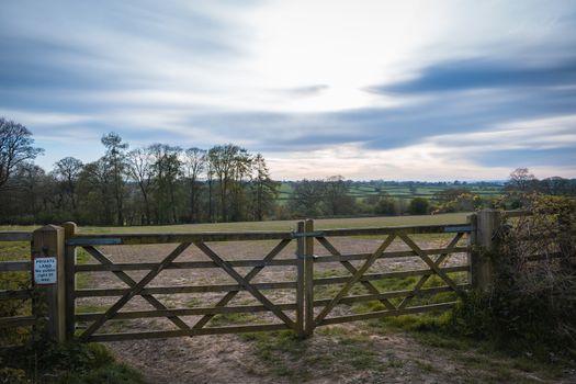 An old rustic wooden farm gate and a beautiful countryside landscape and colorful sky