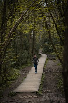 A young woman stood on a wooden pavement path in the countryside