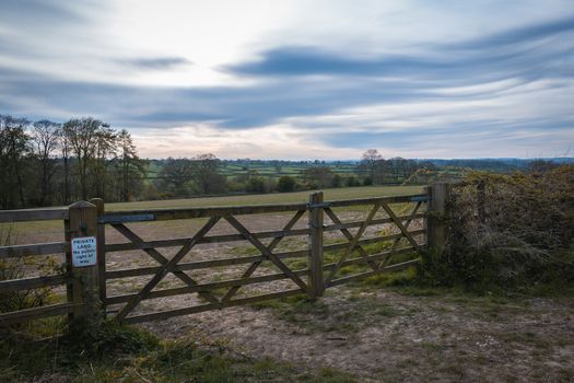 An old rustic wooden farm gate and a beautiful countryside landscape and colorful sky