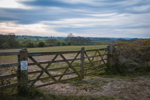 An old rustic wooden farm gate and a beautiful countryside landscape and colorful sky