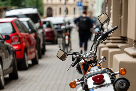 Rear view of powerful motorcycle parked on a sidewalk, defocused street in a background