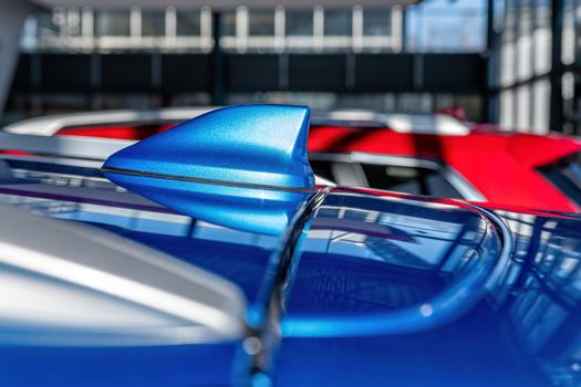 Close up of an FM AM GPS Navigation antenna placed on the roof of a vehicle.  Blurry defocused background - image