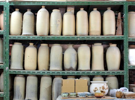 Unfinished ceramic vases are arranged on shelves in a pottery studio

