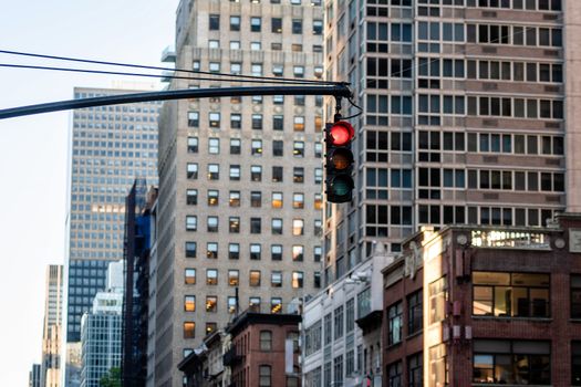 Traffic light with red light above Manhatan street among many skyscrapers, New York, USA