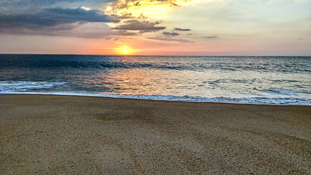 The colors of the sunset on the calm waters of the ocean in Nazaré in Portugal