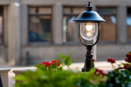 street cafe decorated with lanterns and plants, defocused street landscape in the background