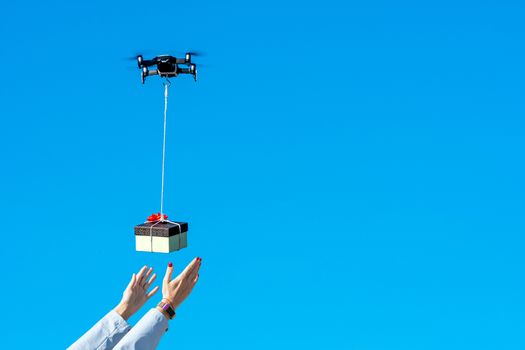 multicopter drone flying with a gift box isolated on a blue sky, concept of modern fast delivery method by using drones
