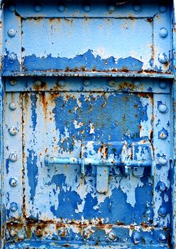 A heavy duty iron door with a bolt and old paint peeling off