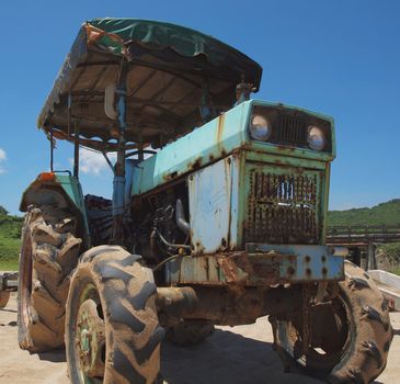 A vintage tractor is parked on a sand beach