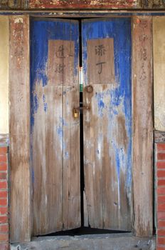 An old wooden door to a Chinese farm house with good luck inscription