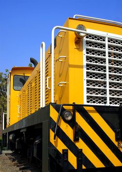 A bright yellow vintage diesel engine designed for narrow railway gauge