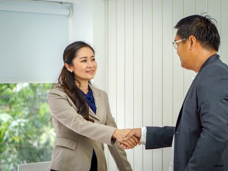Asian female office manager shaking hands during a meeting in the office.