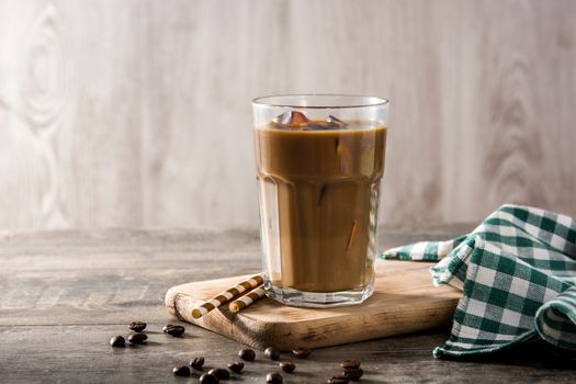 Iced coffee or caffe latte in tall glass on wooden table.