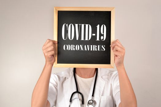 Doctor with a blackboard and message covid-19 and corona virus