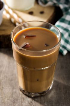 Iced coffee or caffe latte in tall glass on wooden table.