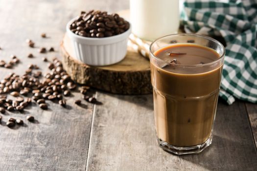 Iced coffee or caffe latte in tall glass on wooden table.