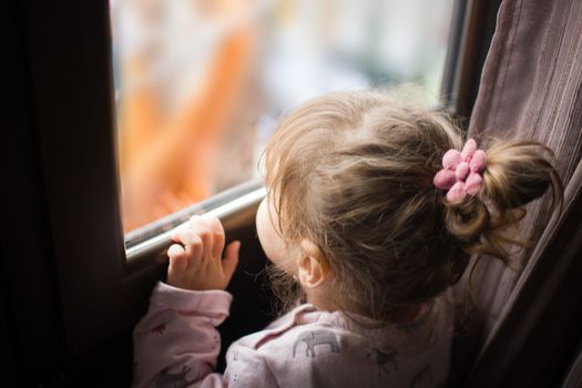 little girl looking out the window. Stay at home concept.