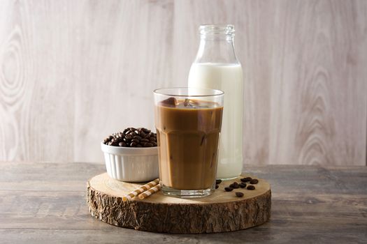 Iced coffee or caffe latte in tall glass on wooden table.