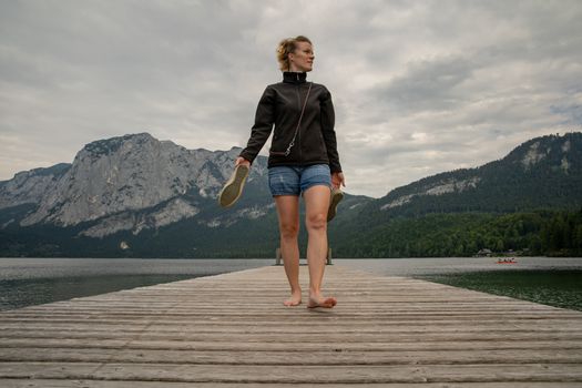 young pretty woman with her black dog enjoying the atmosphere of a mountain lake on the pier