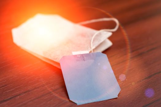 A tea drink in a bag with a label lies on a table in sunny highlights. Fresh tea bag