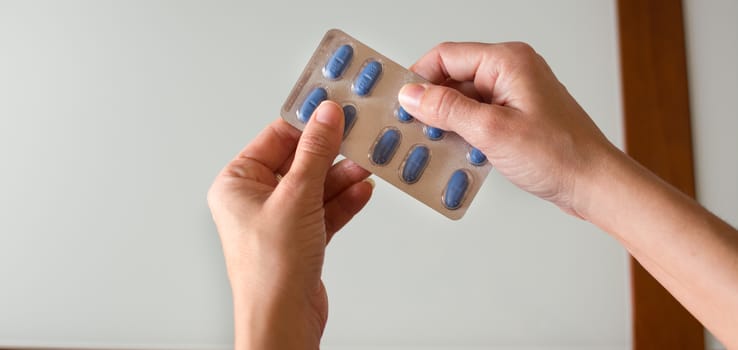 Female hand holding blue medical pills