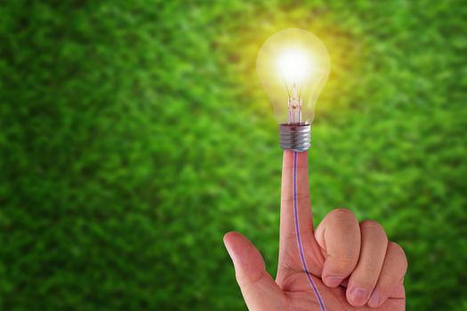 Green energy concept, hand and light bulb on grass background, nature and ecology