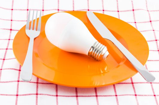 Lamp on orange dish, power consumption concept, selective focus