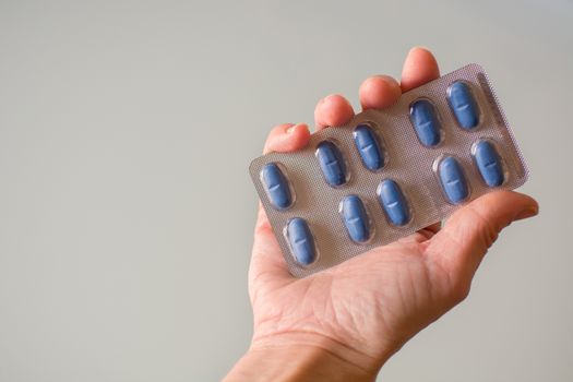 Female hand holding blue medical pills