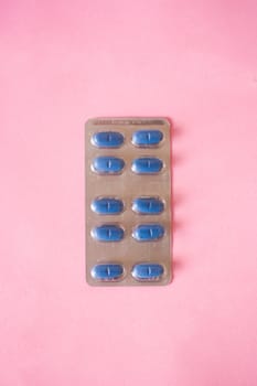 Blue medical pills on pink background