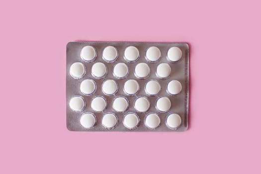 White medical pills on pink background