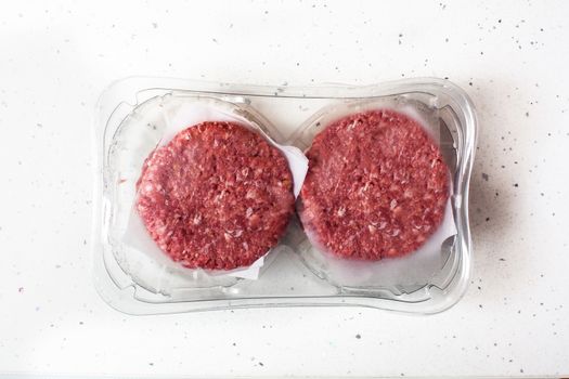 burger meat packaged in plastic on white background