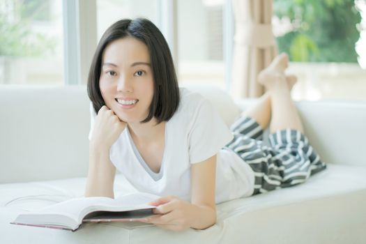 young woman reading a book on the couch