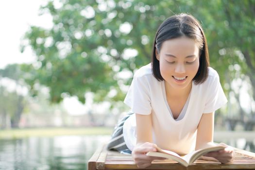 woman reading book in deck chair near swimming pool