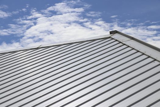 Metal sheet roof and slope with clouds and blue sky background.