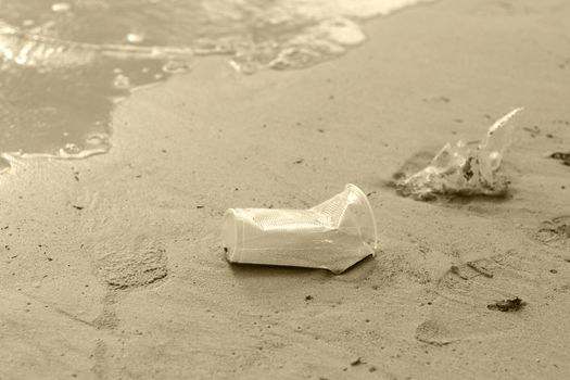 Plastic glass waste is placed at the edge of the beach. Beach garbage