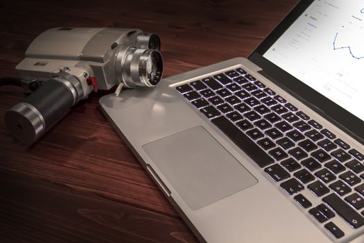 Contrast between different periods of technology: a vintage Super 8 cine camera from the 1960 with an actual computer laptop 