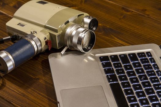 Contrast between different periods of technology: a vintage Super 8 cine camera from the 1960 with an actual computer laptop 