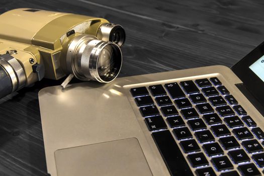 Contrast between different periods of technology: a vintage Super 8 cine camera from the 1960 with an actual computer laptop 