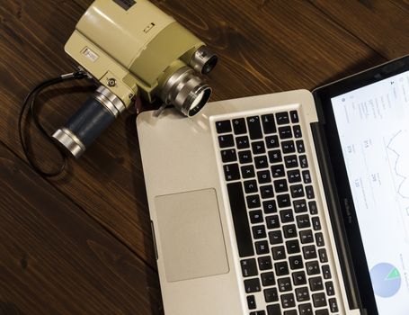 Contrast between different periods of technology: a vintage Super 8 cine camera from the 1960 with an actual computer laptop 