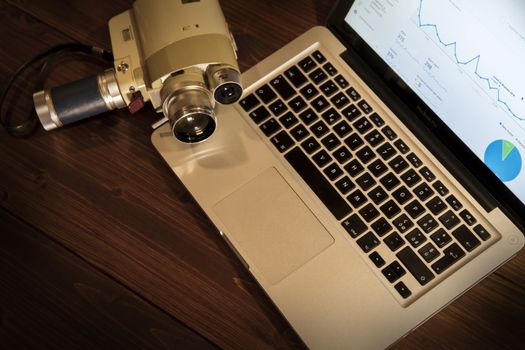 Contrast between different periods of technology: a vintage Super 8 cine camera from the 1960 with an actual computer laptop 