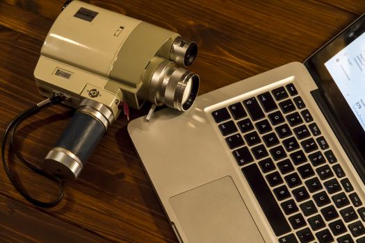 Contrast between different periods of technology: a vintage Super 8 cine camera from the 1960 with an actual computer laptop 