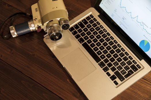 Contrast between different periods of technology: a vintage Super 8 cine camera from the 1960 with an actual computer laptop 