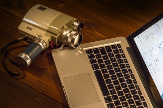 Contrast between different periods of technology: a vintage Super 8 cine camera from the 1960 with an actual computer laptop 