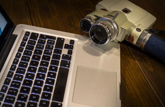 Contrast between different periods of technology: a vintage Super 8 cine camera from the 1960 with an actual computer laptop 