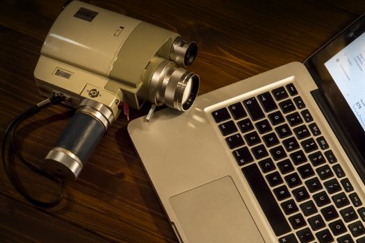 Contrast between different periods of technology: a vintage Super 8 cine camera from the 1960 with an actual computer laptop 