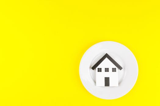 Wooden house toys in a white plate isolated on yellow background,Concept at home and living.
