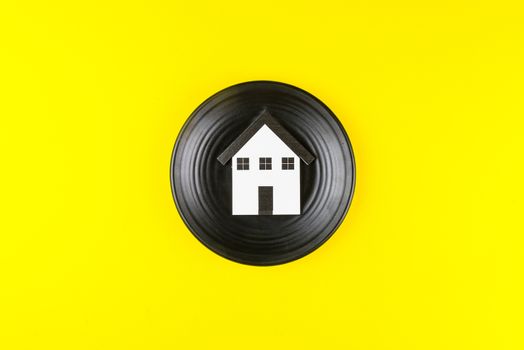 Wooden house toys in a black plate isolated on yellow background,Concept at home and living.